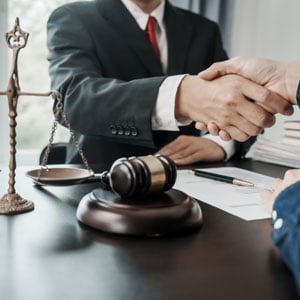 Attorney shaking hands with client over a desk - Escamilla Law Firm