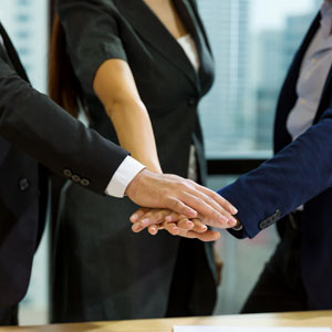 Three professionals shaking hands in agreement symbolizing teamwork and unity - Escamilla Law Firm, PLLC