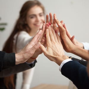 Legal team celebrating success with high fives in an office setting - Escamilla Law Firm, PLLC